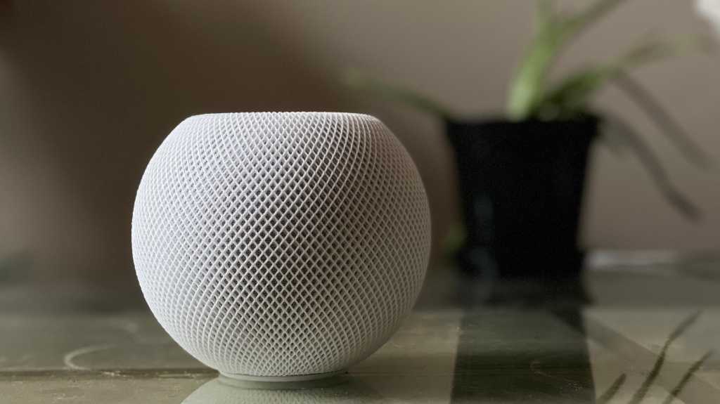 HomePod mini in white ona. table next to a plant